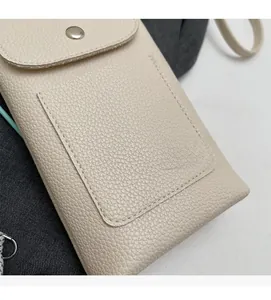 Détail du sac bandoulière beige en cuir grainé montrant la texture douce et le bouton pression