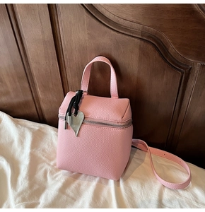 Dettaglio borsa a scatola in pelle rosa con ciondolo a cuore e nappa nera raffinata