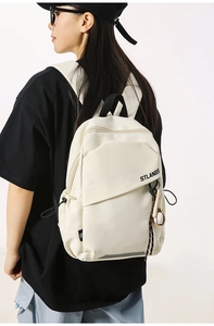 Dettaglio della borsa a tracolla in tela beige con stampa STLANGS e ciondolo da baseball