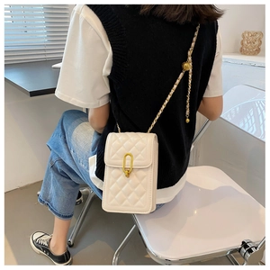 White quilted crossbody bag with gold chain strap shown worn by a model in casual attire