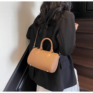 Rear view of a model carrying a brown cylinder Boston bag on wooden stairs