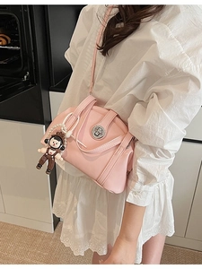Sac bowling rose avec breloque poupée perle porté sur une robe blanche