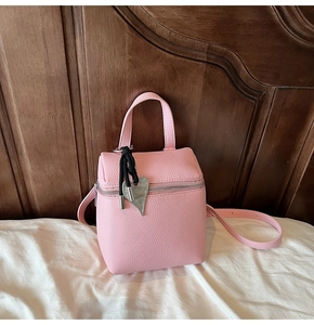 Dettaglio della borsa a mano quadrata rosa con pelle martellata e ciondolo a cuore