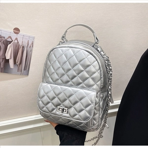 Detail eines silbernen gesteppten Minirucksacks mit Metallic-Finish und Kette