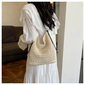 Détail du sac tissé main crème avec bandoulière en cuir marron sur une robe blanche