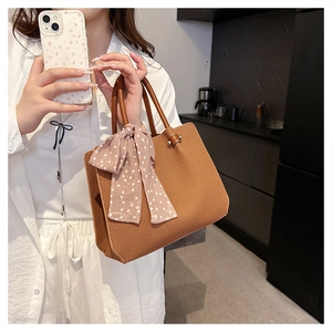 Détail du sac cabas caramel avec texture géométrique et écharpe en soie à pois décorative