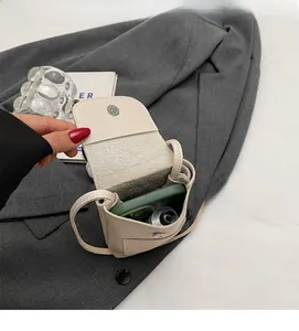 Vue rapprochée de l'intérieur spacieux du mini sac bandoulière blanc crème à texture litchi
