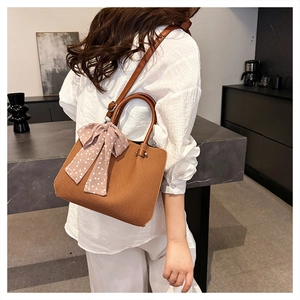 Détail d'un sac seau en cuir caramel avec foulard rose à pois et design épuré