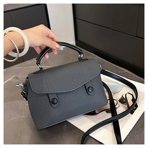 Detail of grey twill textured handbag with black leather handles and silver hardware