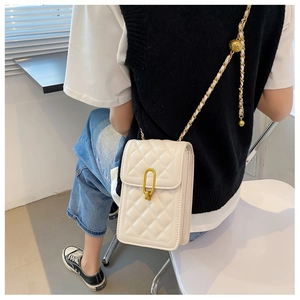 Detail showing white quilted crossbody bag with gold chain and adjustable gold ball buckle