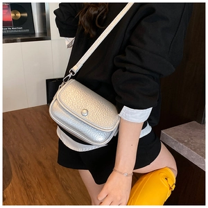 Detail of silver textured leather crossbody bag showing the flap closure and metal button