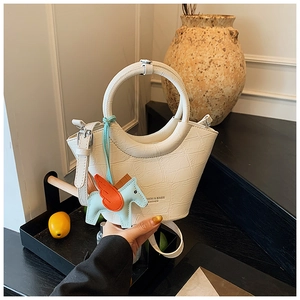White crocodile pattern basket bag with round handles and blue pony charm accessory
