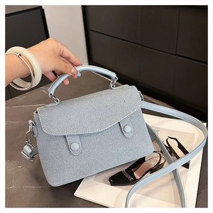 Close-up of light blue crossbody bag featuring striped texture and silver hardware details