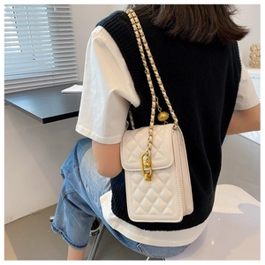 Detailed view of white quilted phone bag featuring a gold ball chain strap on a model