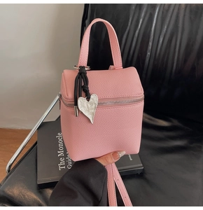 Dettaglio della piccola borsa rosa con trama litchi e ciondolo a cuore in argento