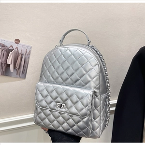 Detail eines silbernen gesteppten Rucksacks mit Metallic-Finish und Kettenriemen