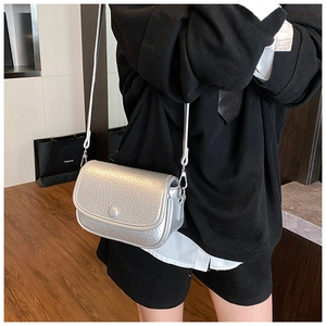 Detail of silver crossbody bag featuring litchi texture leather and metal hardware