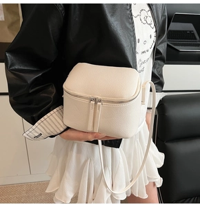 Detailaufnahme der weißen Umhängetasche aus Leder mit Litschi-Muster und Reißverschluss