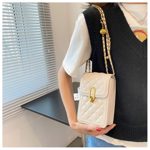 Detail of quilted crossbody phone bag with gold ball chain and oval metal lock