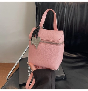 Dettaglio borsa rosa in pelle litchi con grande ciondolo a cuore in argento sulla zip