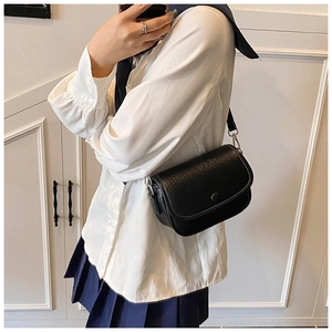 Detail of a black pebbled leather crossbody bag with silver hardware and magnetic closure