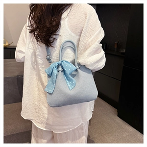 Vue détaillée du sac seau bleu clair tissé avec nœud à pois et boucles argentées