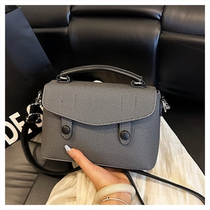 Close-up of gray twill texture and black circular buckles on a stylish crossbody bag