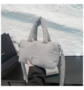 Gros plan du sac cabas matelassé gris avec poignées rembourrées et bandoulière longue