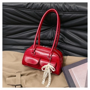 Détail d'un sac bowling en cuir ciré rouge avec poches vintage et nœud en dentelle