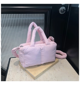 Vue détaillée du cabas matelassé rose clair sur livre d'art avec fond de style industriel
