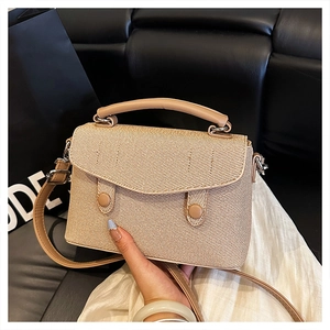 Close-up of small light brown woven handbag featuring textured flap and twin button detail