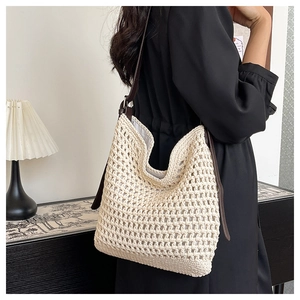 Détail du sac seau en paille tressée avec maille ajourée crème et anses en cuir marron