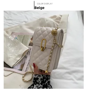 Detail of beige quilted mini crossbody bag with gold chain strap and adjustable ball