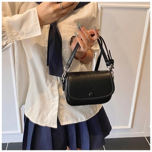 Close-up of black lychee texture flap bag with silver hardware on a school style outfit