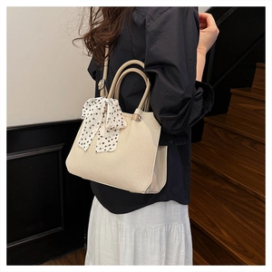 Détail du sac cabas en toile beige avec un foulard décoratif à pois noirs et blancs