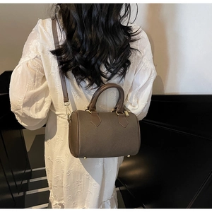 Brown barrel Boston bag with textured leather and gold hardware shown on a model