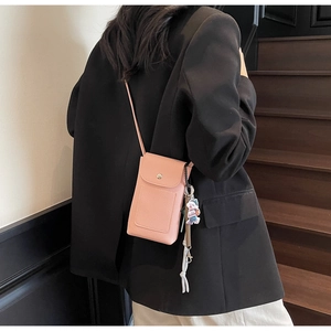 Sac bandoulière rose pour téléphone en cuir grainé porté par un mannequin en intérieur