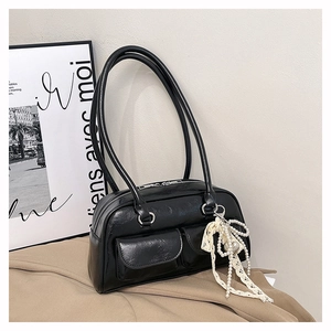 Détail du sac bowling noir montrant le nœud en dentelle latérale et le pendentif en perles