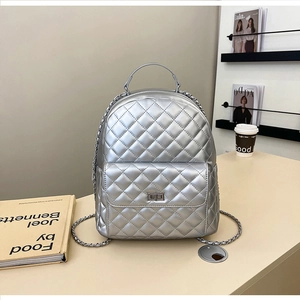 Detail eines silbernen gesteppten Rucksacks mit Metalldrehverschluss und feinen Kettenriemen