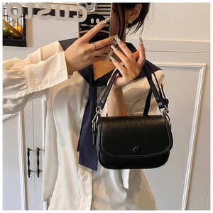 Close-up of black lychee grain leather handbag with top handle and metal clasp