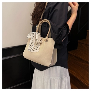 Détail du sac seau tissé beige avec foulard en soie chic à pois élégant décoratif