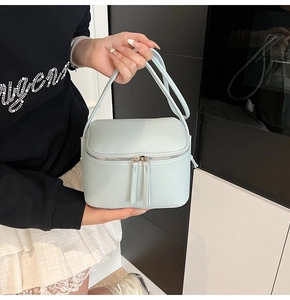 Detail der hellblauen Mini-Tasche aus Leder mit Lychee-Maserung und silbernen Reißverschlüssen