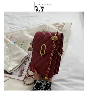 Detail view of wine red quilted bag with gold chain strap and accordion side design
