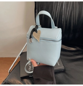 Dettaglio della borsa azzurra a scatola con grana litchi e zip con ciondolo a cuore