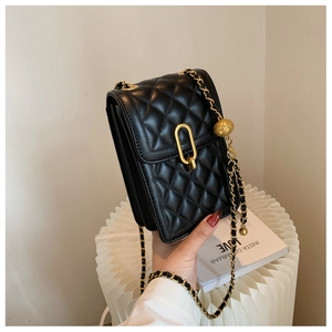 Detail of black quilted leather crossbody bag with gold lock and sliding metal ball chain