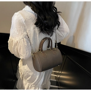 Detailed view of the brown leather boston bag with golden hardware and adjustable strap