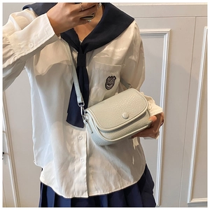 Close-up of a light blue litchi pattern leather crossbody bag worn by a model