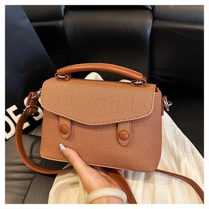 Detail of caramel woven texture on small square crossbody bag with metallic buckles