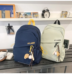 Dettaglio di borse a tracolla in nylon blu e verde con logo e ciondoli da baseball