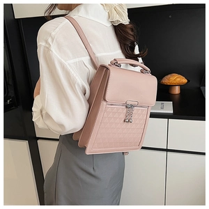 Detail of pink quilted backpack with silver hardware and tassel charms on a model
